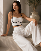 Model seated wearing the Intyra Ivory Contour Corset Top featuring contrast piping and modern sculpted styling.